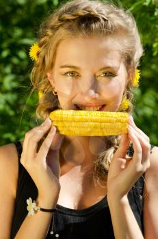 Close-up outdoor portrait of young beauty woman eating corn-cob