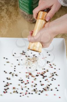 Close-up of woman hand using a pepper mill to season his food