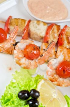 Closeup of grilled salmon and shrimps with tomatoes and peppers on bamboo sticks