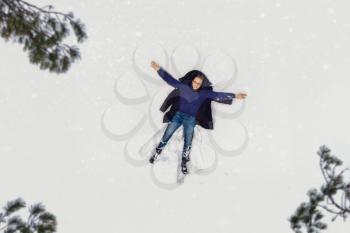 Aerial view to woman lying in snow and making snow angel