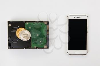 Bitcoin coin on the HDD and phone on a white