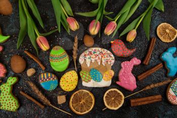 Tulips and gingerbread cookies on darken concrete background for Easter.