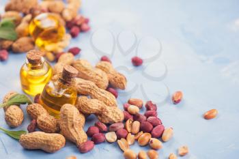 Natural peanuts with oil in a glass jar on the blue concrete background