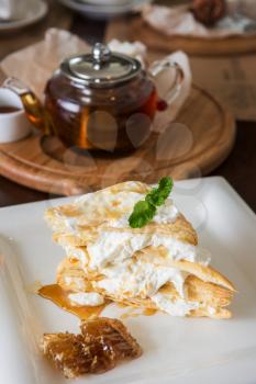 Honey cake with vanilla cream at white plate
