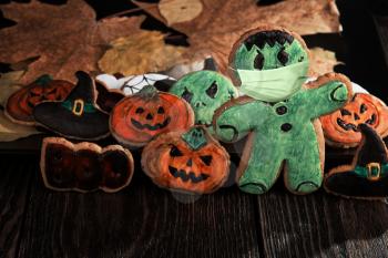 Ginger biscuits with face mask for Halloween holiday on wooden, concept of covid hallowen