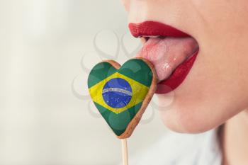 Closeup photo of the woman lips and cookie hearts with flag of Brazil