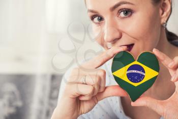 Young woman with gingerbread heart cookies with flag of Brazil