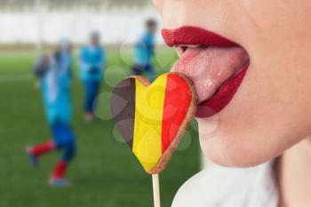 Closeup photo of the woman lips and cookie hearts with flag of Belgium