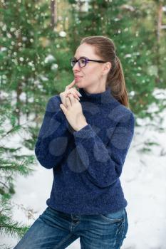 Portrait of pretty woman in a woolen blue sweater in the winter forest. Winter holidays concept or forest walking.