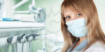Female dentist in protective mask and whitecoat
