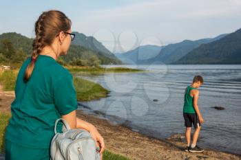 Woman and her son resting on Teletskoye lake in Altai mountains, Siberia, Russia. Beauty summer day.