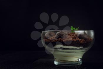 Chocolate dessert of cookies with pieces of chocolate and mint on a dark wooden background with copyspace, food and drink concept