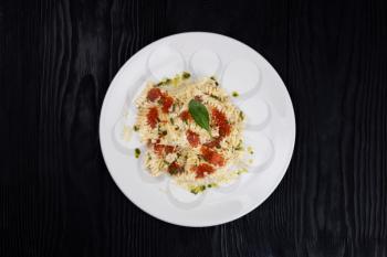 Seafood Pasta with red caviar in white plate on black wooden background.