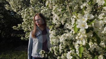 Beauty woman enjoying nature in spring apple orchard in Garden with blooming trees.