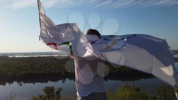 BARNAUL CITY. RUSSIA - JUNE 08, 2021: Boy waving flag the Olympic Games outdoors over cloudy sunset sky. Children sports fan. Summer olympic games on June 08, 2021 in Altayskiy krai, Siberia, Barnaul, Russia