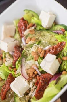 Salad feta cheese lettuce sausage cucumbers and pine nuts