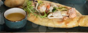 Georgian dish khachapuri with seafood and fresh vegetables close-up 