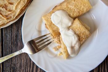 Fried pancakes  with sour cream on old wooden table