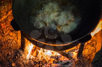 Camping fire and kettle with frying fish