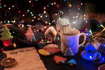Christmas cookies and cup of tea on daark color bokeh lights background