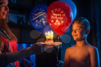 mother congratulates her son with birthday, gives cake with candles