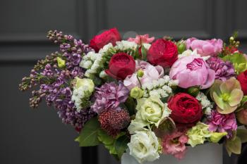 Bouquet of different beauty flowers in round present box on dark background