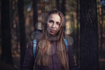 Pretty happy woman posing in forest and looking at camera.