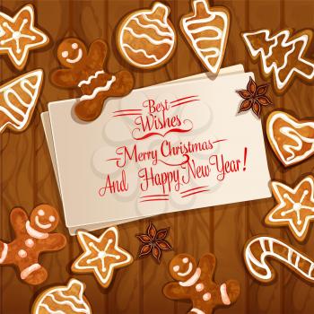 Christmas gingerbread man, xmas tree and ball, candy cane, star, heart cookie and anise placed around greeting card with wishes of Merry Christmas. Wooden background with ginger cookie for xmas design