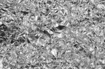 Silver foil background with shiny crumpled uneven surface for texture and background