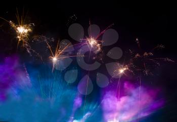 Fireworks in the lilac and blue smoke at night in the sky useful as festive background
