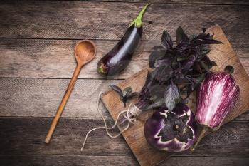 Aubergines and basil on and wooden table. Rustic style and autumn food photo