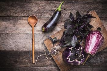 Aubergines, basil and spoon on wooden table. Rustic style and autumn food photo