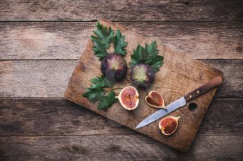 rustic style Cut figs with knife on chopping board and wooden table. Autumn season food photo