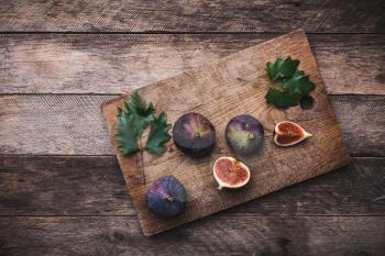 Cut Figs on chopping board and wooden table. Autumn season food photo