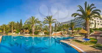Panorama of swimming pool and palm trees at luxury resort. Summer Vacation