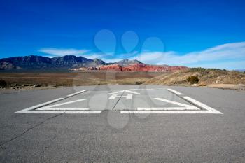Helicopter pad against the dry landscape and red rock formations of the Mojave Desert.