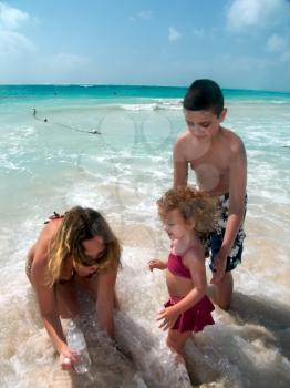 Happy family playing in the surf on the caribbean beach.