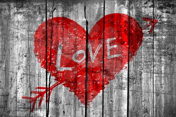 Drawing of abstract heart pierced by an arrow with word Love on grunge wooden wall background