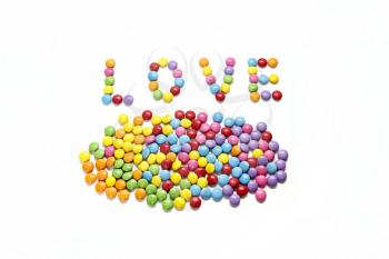 Word ''Love'' and bright colorful candy on white background