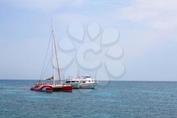 RED SEA / EGYPT - OCTOBER 19, 2012: White boats, red catamaran and floating people on a sea walk in the beautiful sea