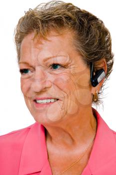 Happy senior woman wearing a bluetooth isolated over white