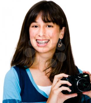 Teenage girl photographing with a camera and smiling isolated over white