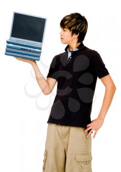 Teenager showing a stack of laptops and posing isolated over white