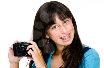 Asian teenage girl photographing with a camera and smiling isolated over white