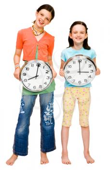 Smiling girls holding clocks isolated over white