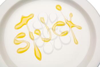 Stuck written with honey on a plate isolated over white