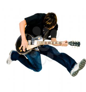 Teenager playing a guitar and jumping isolated over white