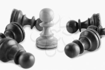 White chess pawn surrounded by black chess pawns