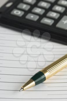 Close-up of a ballpoint pen with a paper and calculator
