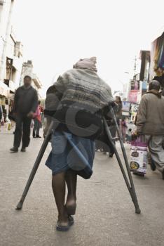 Rear view of a disabled man in a street market, New Delhi, India